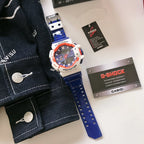 Casio G-Shock watch with blue silicone strap, white case, and orange protective bezel
