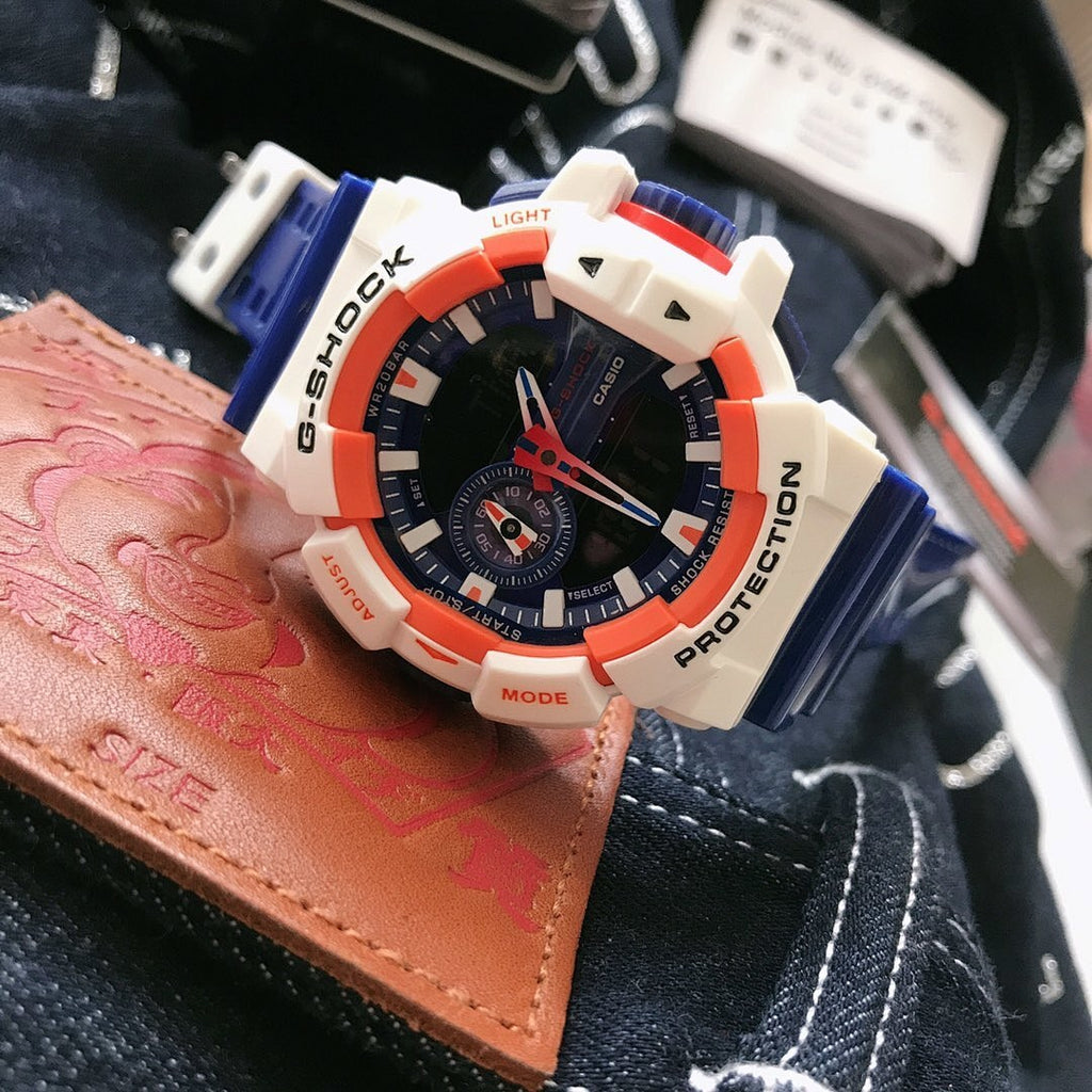 Casio G-Shock watch with blue strap, white case, orange bezel, black dial