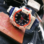 Casio G-Shock watch with blue strap, white case, orange bezel, black dial