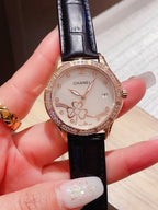 Chanel watch with black leather strap and diamond bezel, floral dial on hand