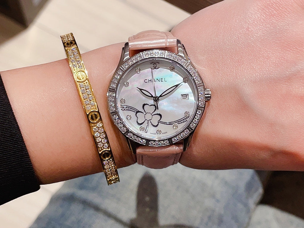 Chanel watch with light gray leather strap, white dial, diamond bezel, and flower motifs
