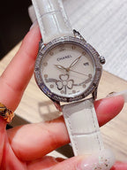 Chanel watch with white leather strap, white dial, diamond bezel, and flower details