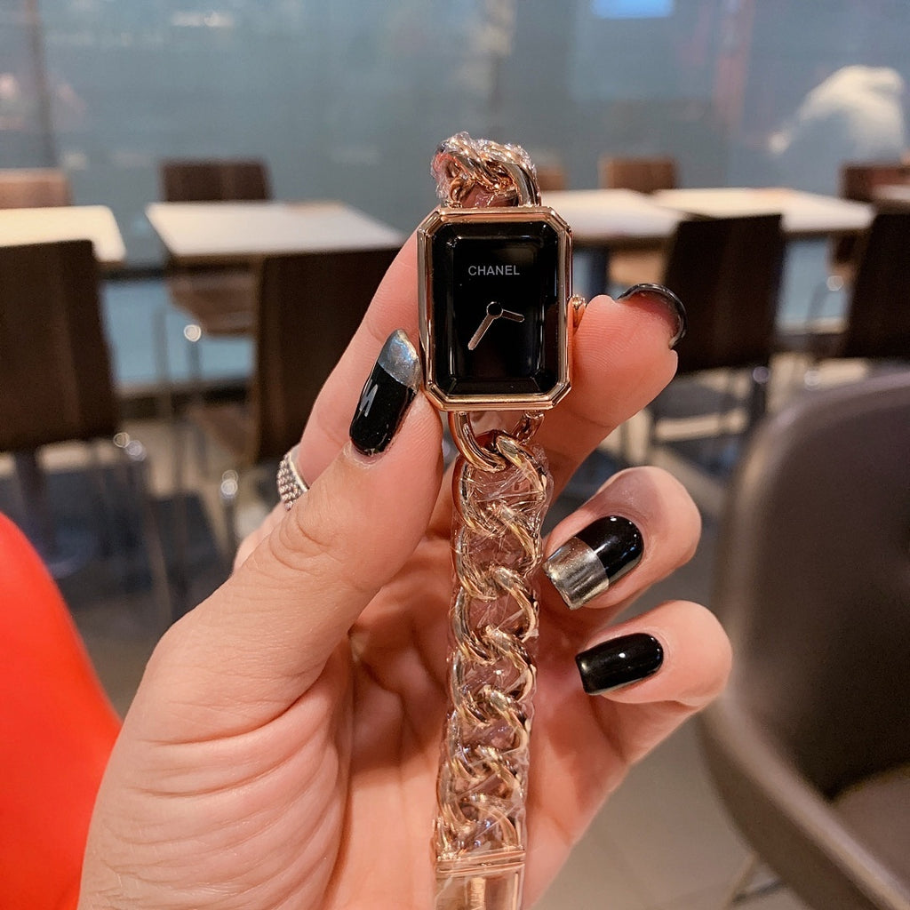 Gold-toned chain-link Chanel watch with black rectangular dial and crown detail.