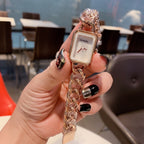 Gold-toned chain-link Chanel watch with white rectangular dial and slim bezel.