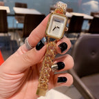 Gold-toned chain-link Chanel watch with white rectangular dial and round hands.