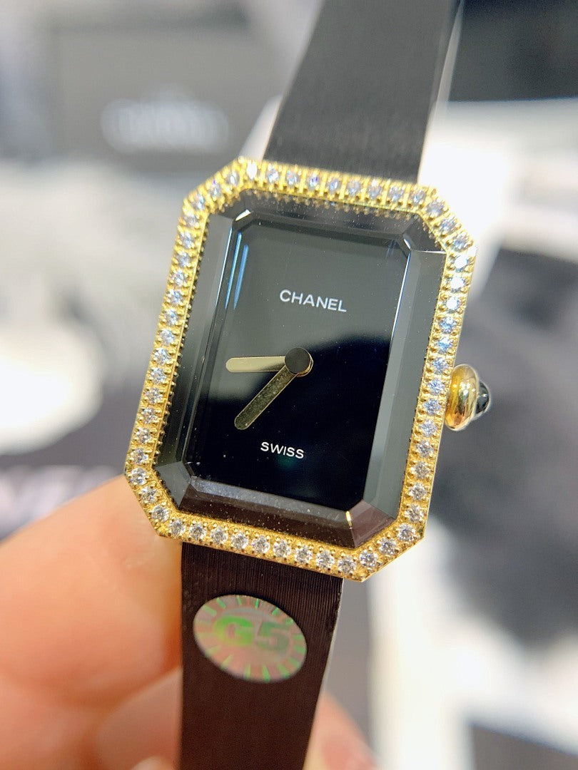 Gold-tone rectangular watch with black dial, jeweled border, and black leather strap