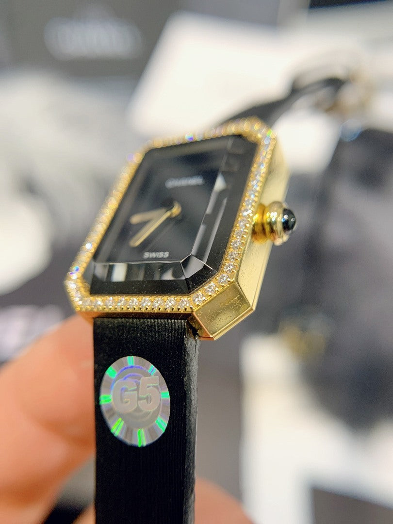 Gold-tone rectangular watch with black dial, jeweled bezel, and black leather strap