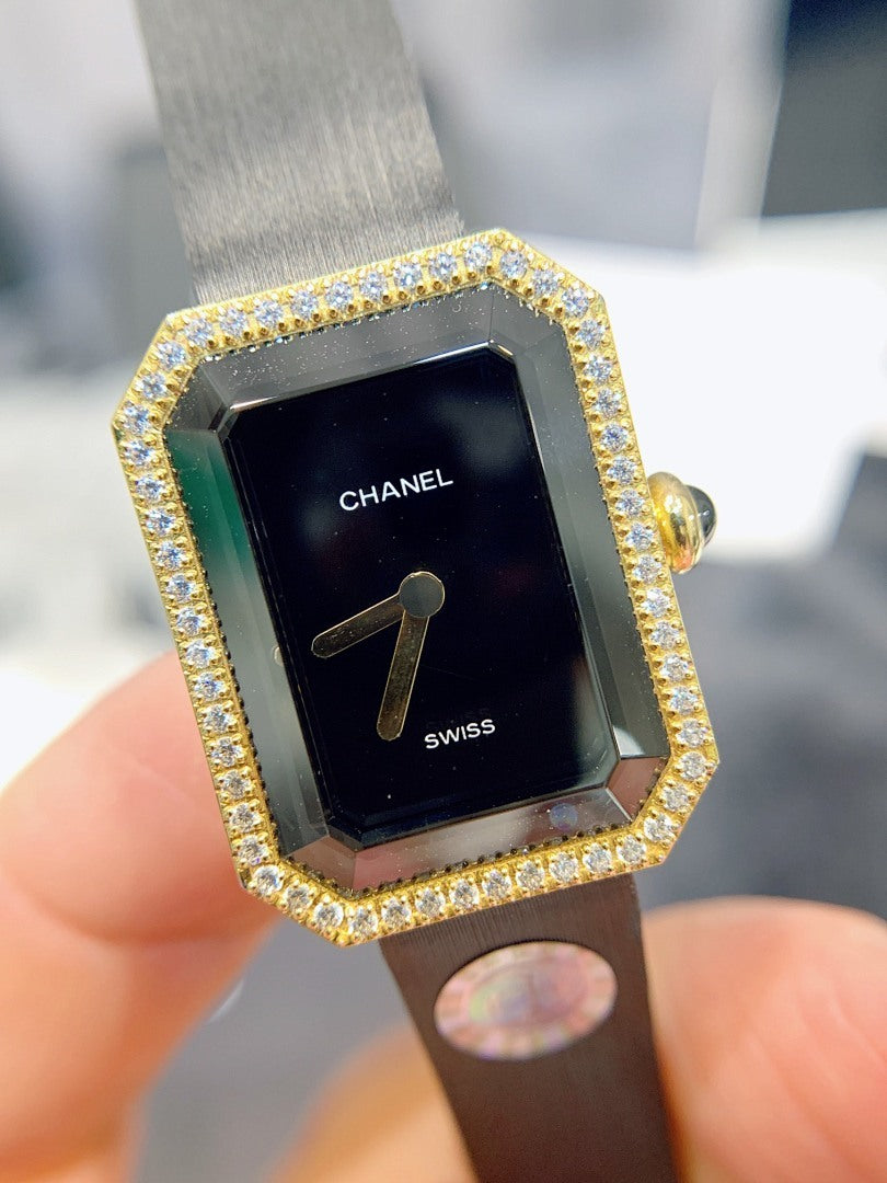 Gold-tone rectangular watch with black dial and jeweled bezel, black leather strap