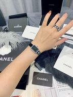Chanel wristwatch on wrist with dark leather strap and square silver bezel
