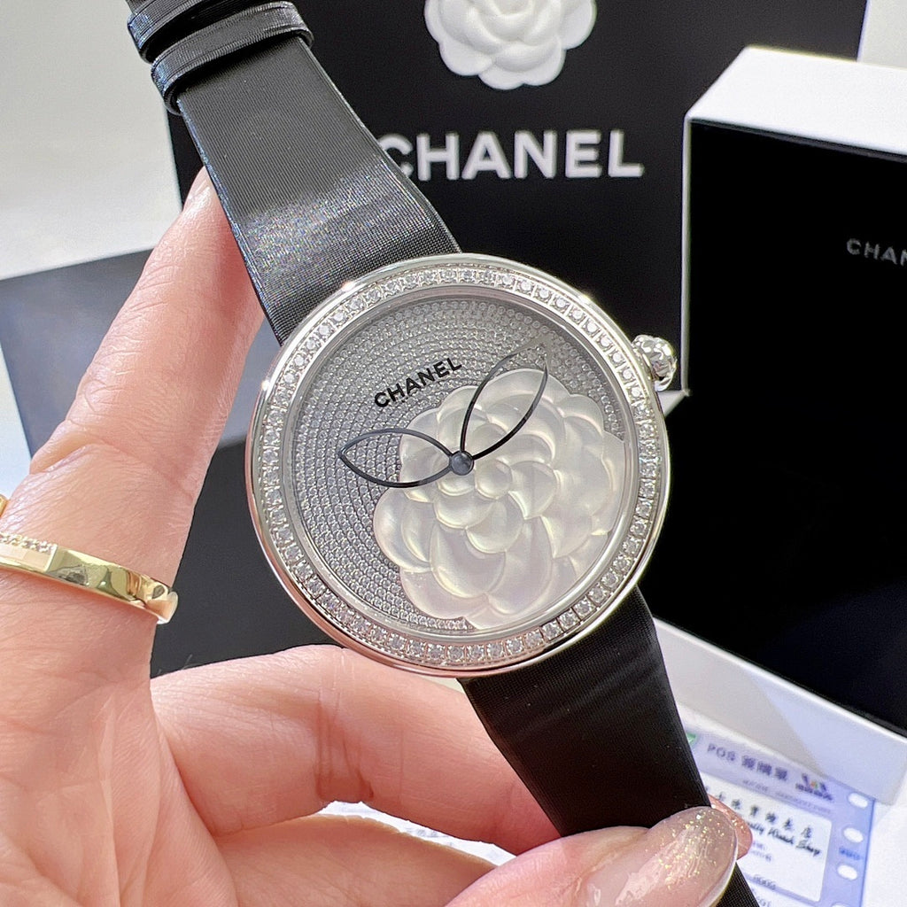 Chanel round wristwatch close-up of silver floral dial and black leather strap