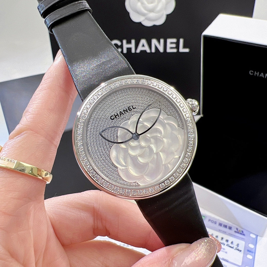 Chanel round wristwatch close-up of silver floral dial and black leather strap