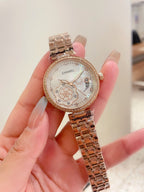 Chanel watch with rose-gold tone case, rhinestone bezel, and rose-gold metal link bracelet