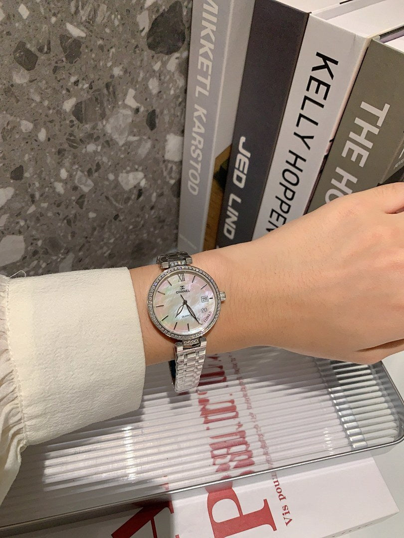 Chanel watch on wrist with silver bracelet and light dial, baton markers