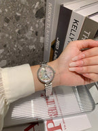 Chanel watch on wrist with silver bracelet and light dial with minute markers