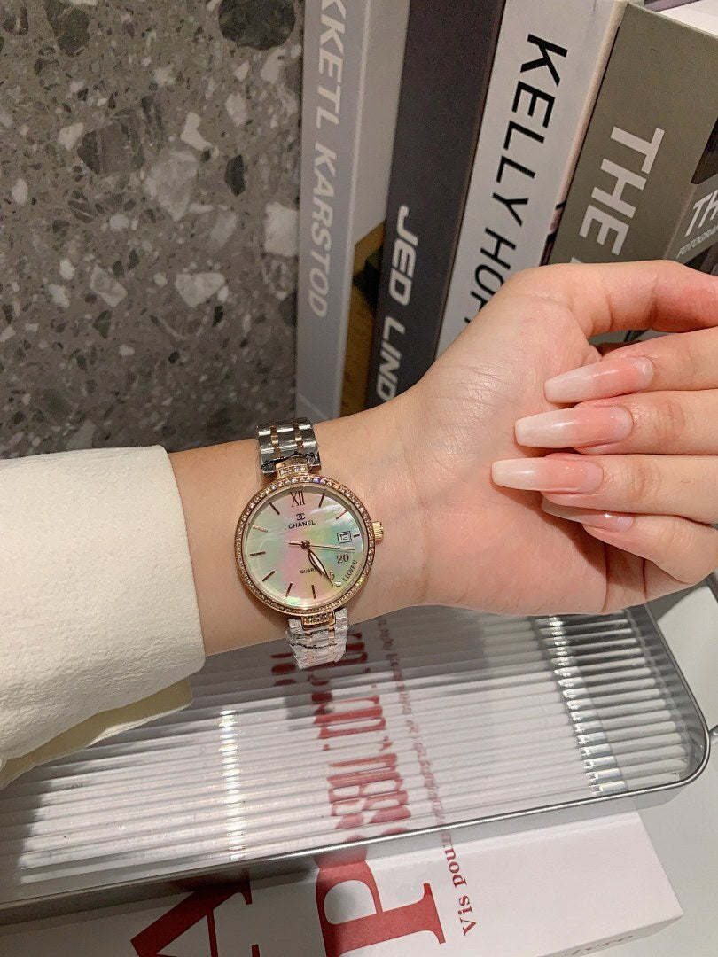 Chanel watch on wrist with silver bracelet and pale dial with colorful accents