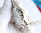 Silver Chanel wristwatch with white dial, metal case and bracelet links, side profile.