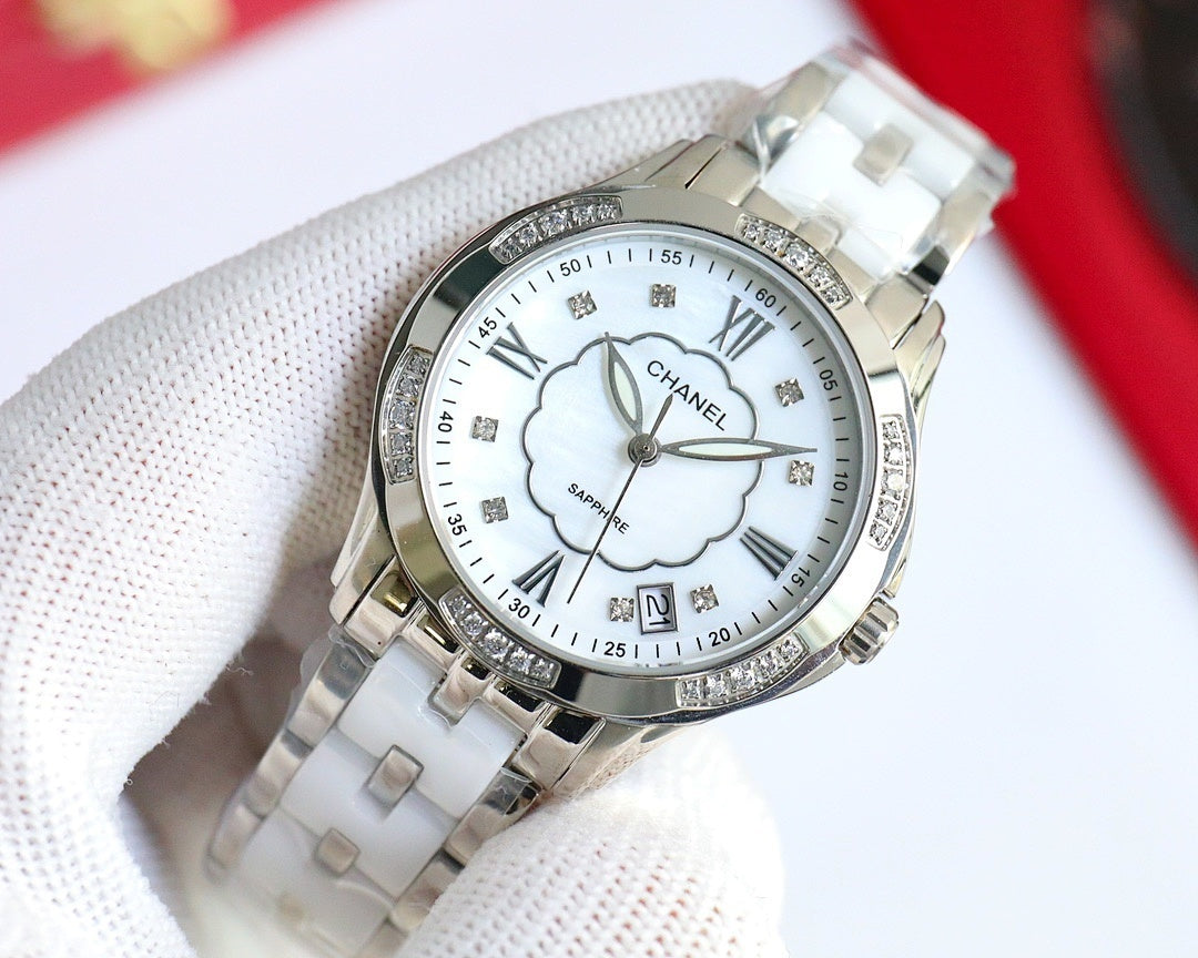 Silver Chanel watch with white dial, clover motif, Roman numerals, polished metal bracelet.