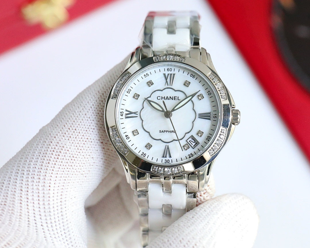 Silver Chanel watch with white dial, clover motif, Roman numerals, polished metal bracelet.