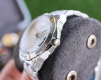 Analog watch case back with silver finish, engraved text and bracelet links