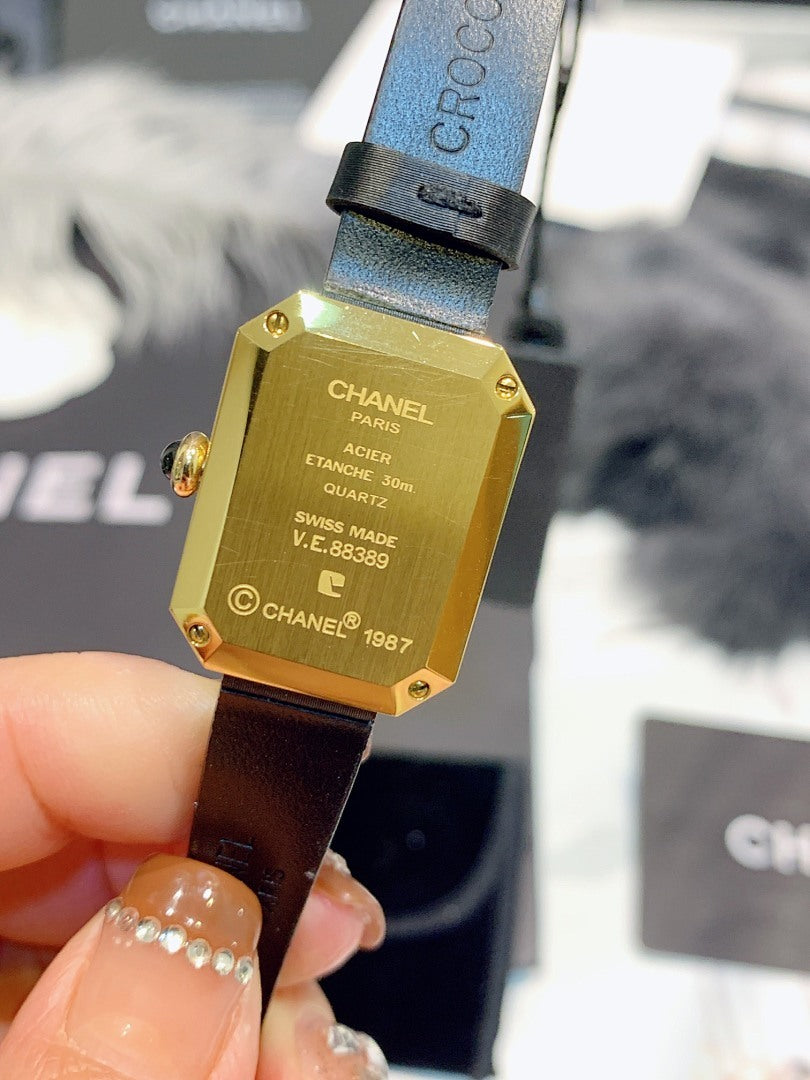Chanel watch gold-tone case back with engraved text, on dark leather strap