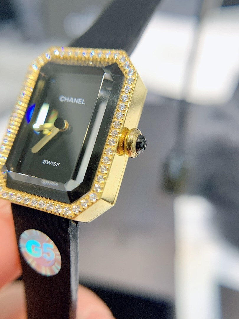 Chanel watch front close-up: gold diamond bezel, black dial, black leather strap