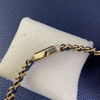 Gold-tone side of a watch case with small round detail on a navy blue chain bracelet