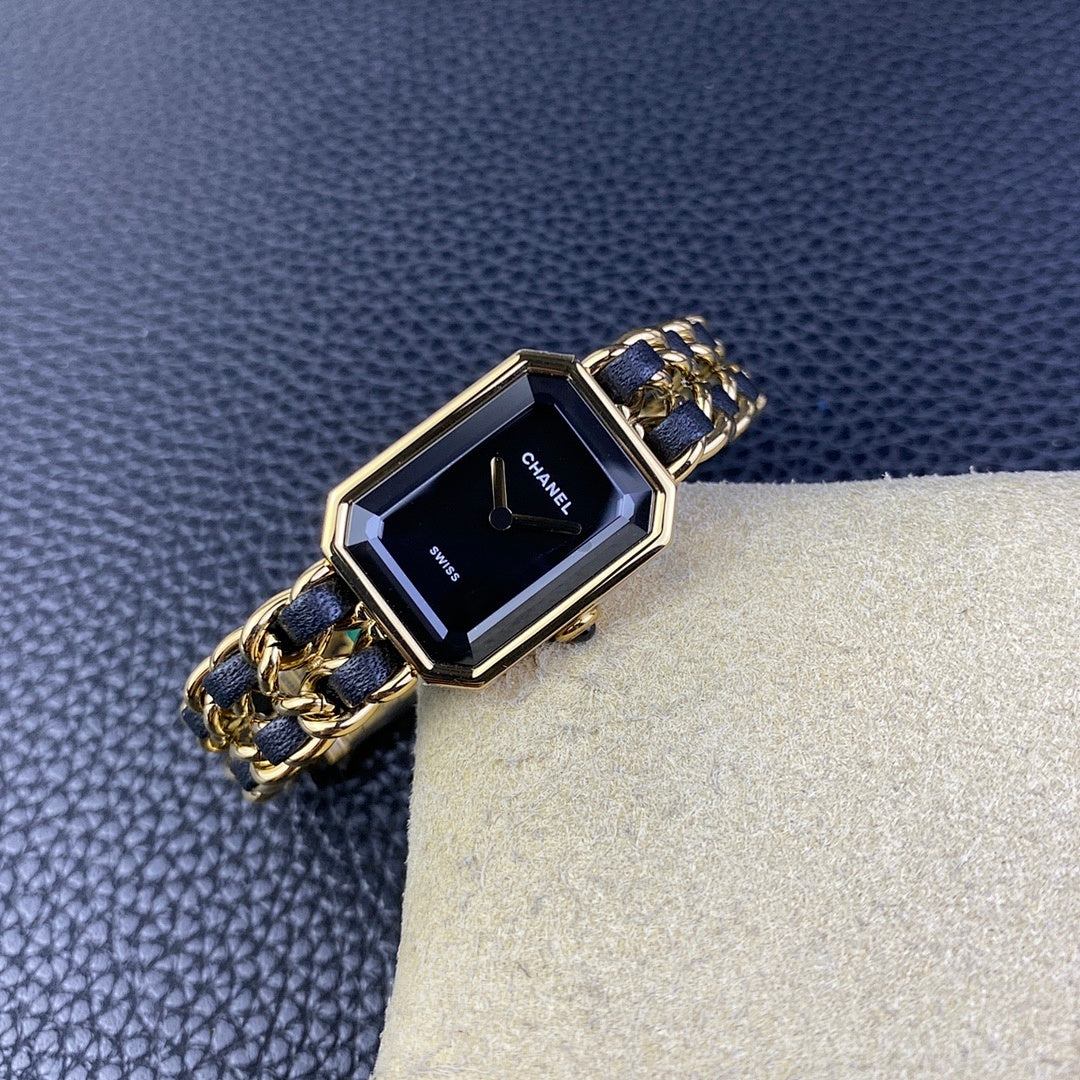 Gold-tone rectangular watch with navy blue link bracelet and dark dial on cream cushion