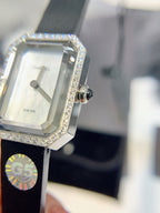 Rectangular Chanel watch with diamond bezel, silver dial, and black strap