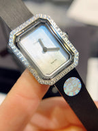 Rectangular Chanel watch with black strap and diamond bezel over silver dial