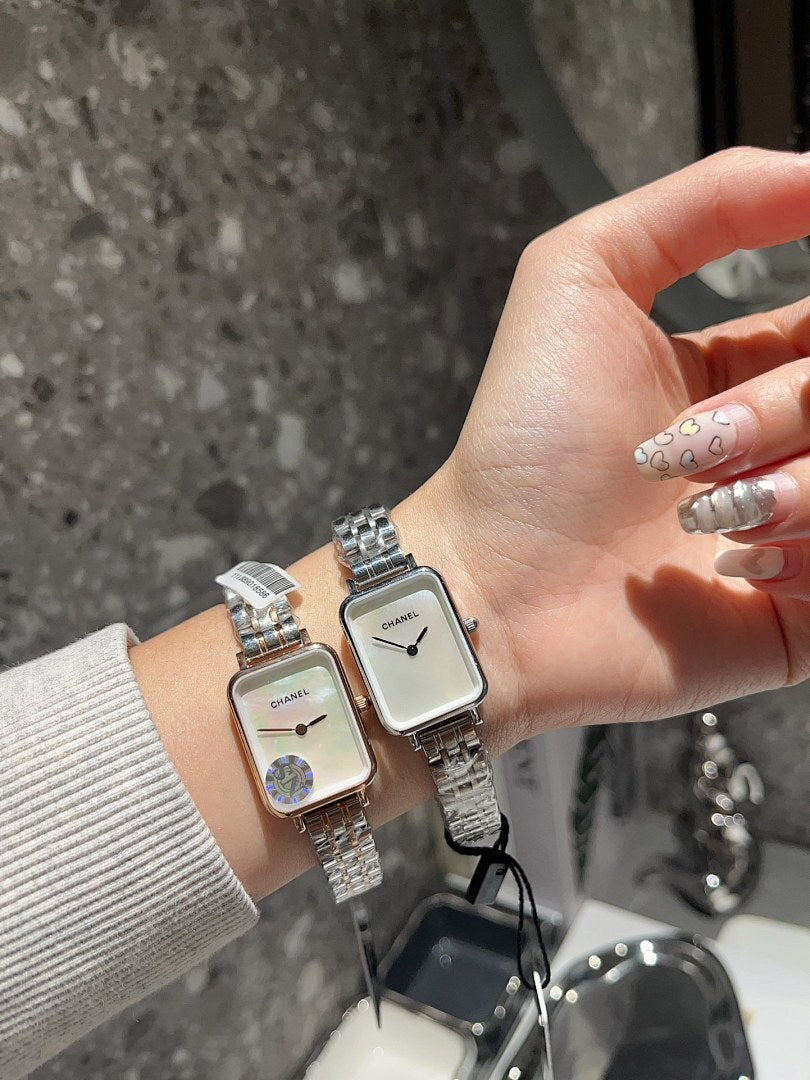 Rectangular wristwatch with silver-tone metal bracelet and white dial on a hand