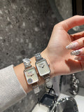 Rectangular wristwatch with silver-tone metal bracelet and white dial on a hand