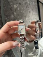 Rectangular CHANEL wristwatch with silver-tone link bracelet and white dial held up