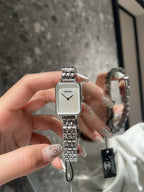 Rectangular wristwatch with silver-tone metal bracelet and white dial with black hands