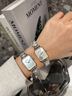 Pair of rectangular wristwatches with silver-tone bracelets and white dials on a wrist