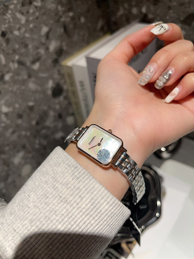 Rectangular wristwatch with silver-tone metal bracelet and white dial on a hand