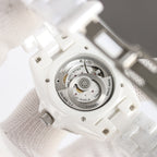 Chanel watch caseback on white ceramic strap, metal movement detail visible.