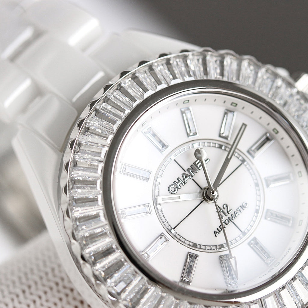 Chanel watch with white dial and Roman-style markers, silver diamond-like bezel, close-up.