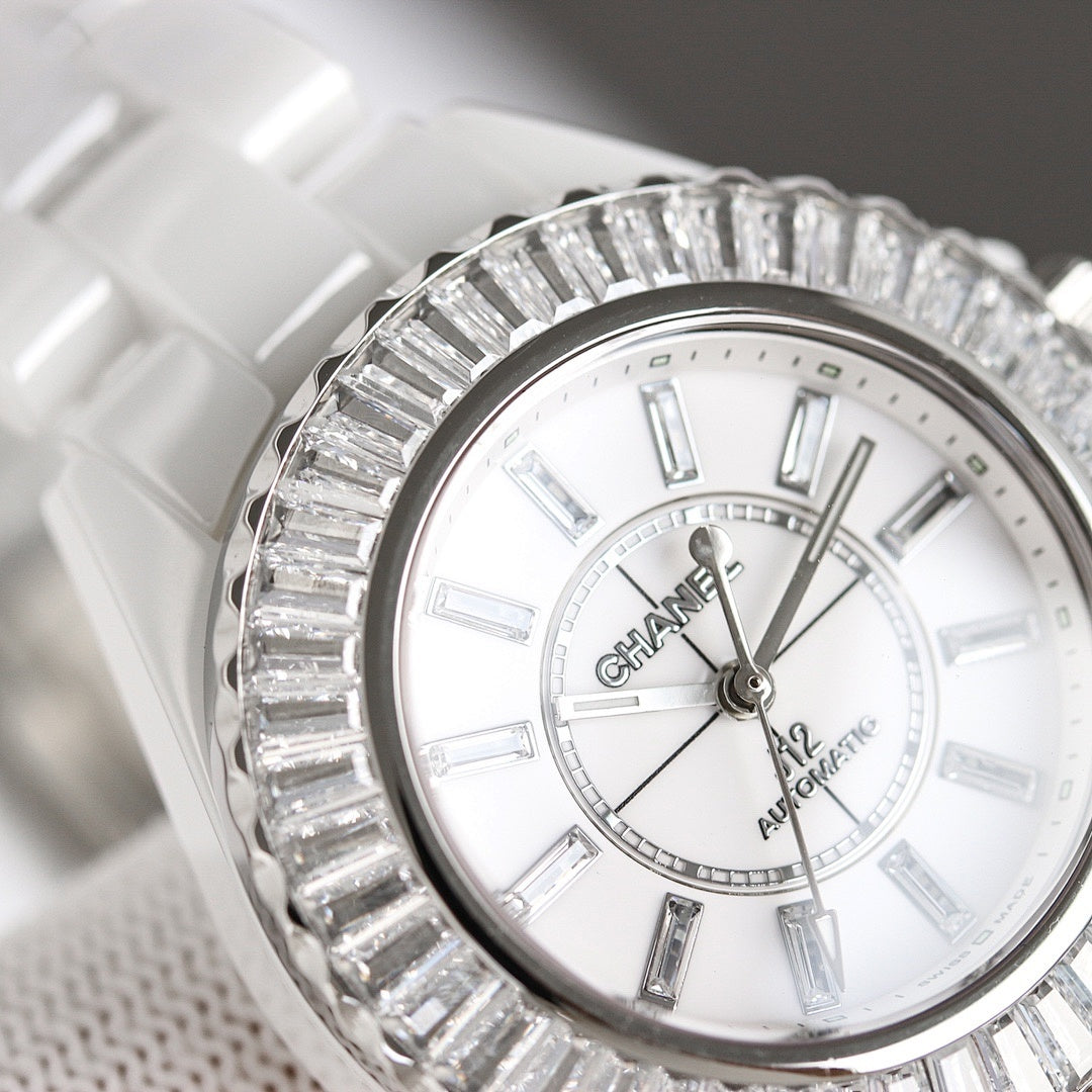 Chanel watch with white dial and Roman-style markers, silver diamond-like bezel, close-up.