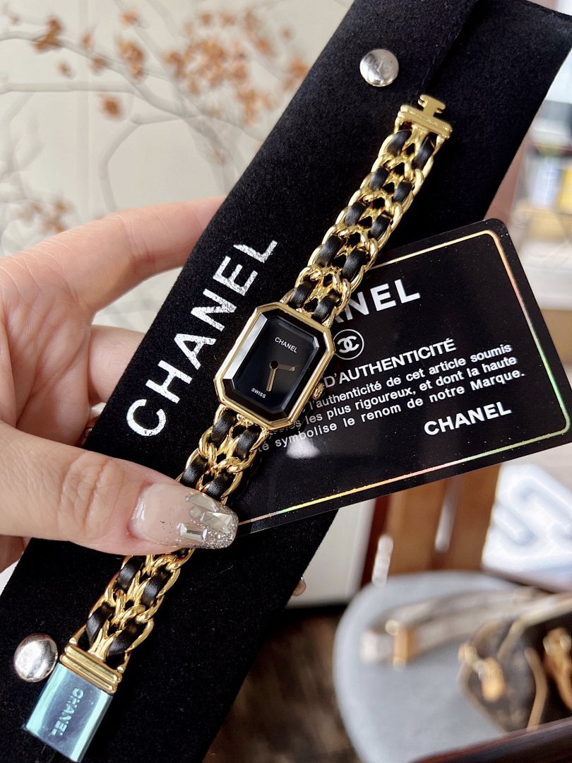Chanel watch with black face and gold-tone linked bracelet, held in hand