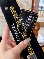 Chanel watch close-up showing black dial, gold-tone case, and linked band