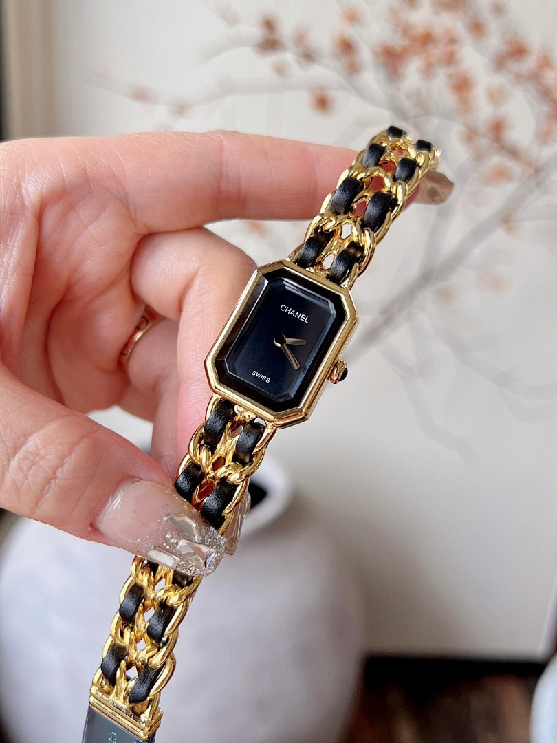 Chanel watch with black dial and gold-tone linked band, held upright