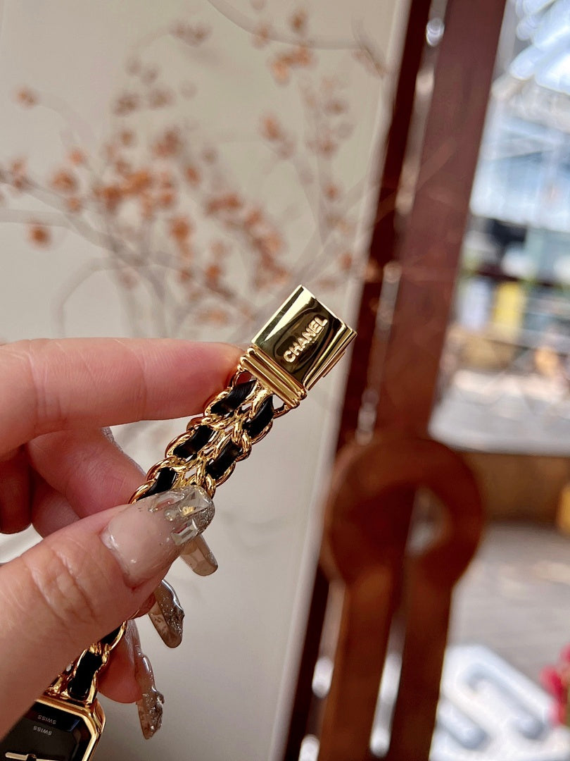 Chanel watch with gold-tone case, black dial, and linked bracelet