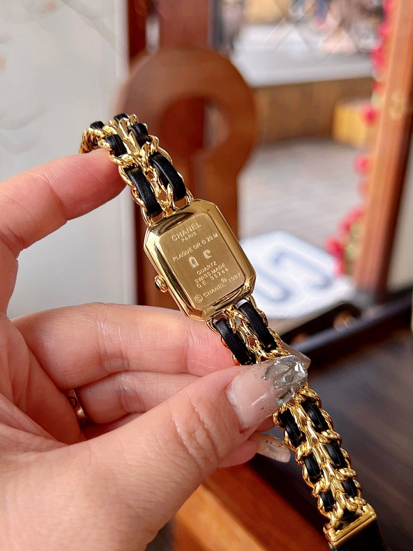 Chanel watch on gold-tone bracelet with black face and gold hands