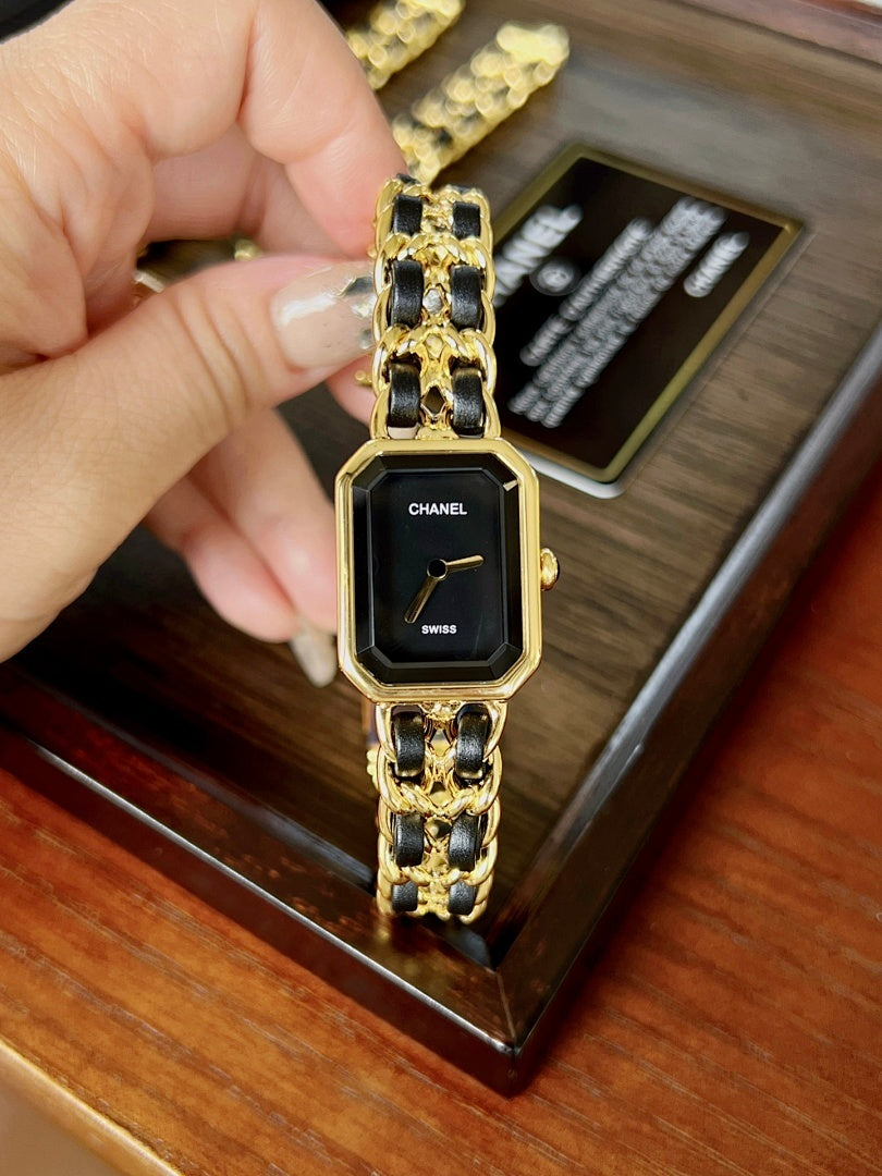 Chanel watch on wrist with gold-tone link bracelet and black square dial