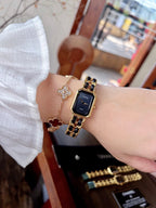 Chanel watch on wrist with gold-tone bracelet; black dial with gold markers