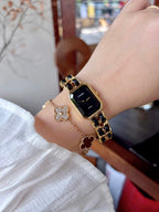 Chanel watch on wrist with gold-tone link bracelet and black square dial