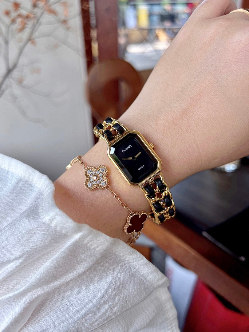 Chanel watch on wrist with gold-tone link bracelet and black square dial
