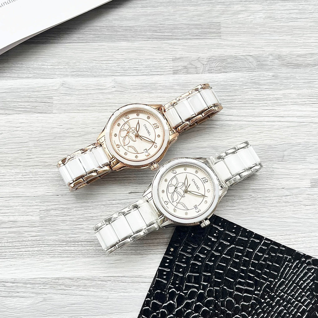 Two Chanel watches on a tabletop: white metal bracelets with rose-gold and silver dials