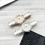 Two Chanel watches on a tabletop: white metal bracelets with rose-gold and silver dials