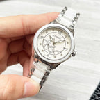 Chanel watch with white metal bracelet and silver-tone floral dial, close-up